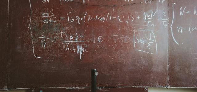 written equations on brown wooden board by Roman Mager courtesy of Unsplash.